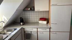 Uma cozinha com pia, armários e bancada.