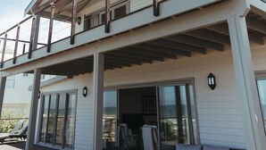 Un bâtiment à deux étages doté d’un balcon, d’un espace extérieur aménagé pour s’asseoir et de grandes fenêtres.