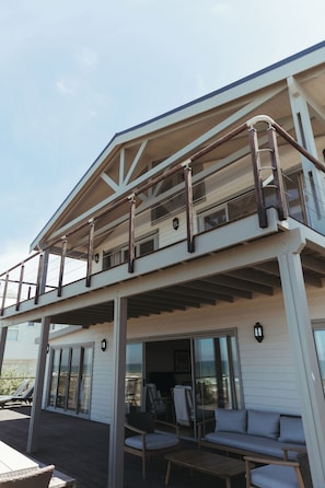 A two-story building with a balcony, outdoor seating area, and large windows. - Luxury 4 Bedroom Beachfront Villa/Private Pool & Ocean Views (Yzerfontein)