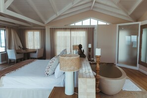 A spacious bedroom with a large bed, a sitting area with a table and chairs, and a large mirror.