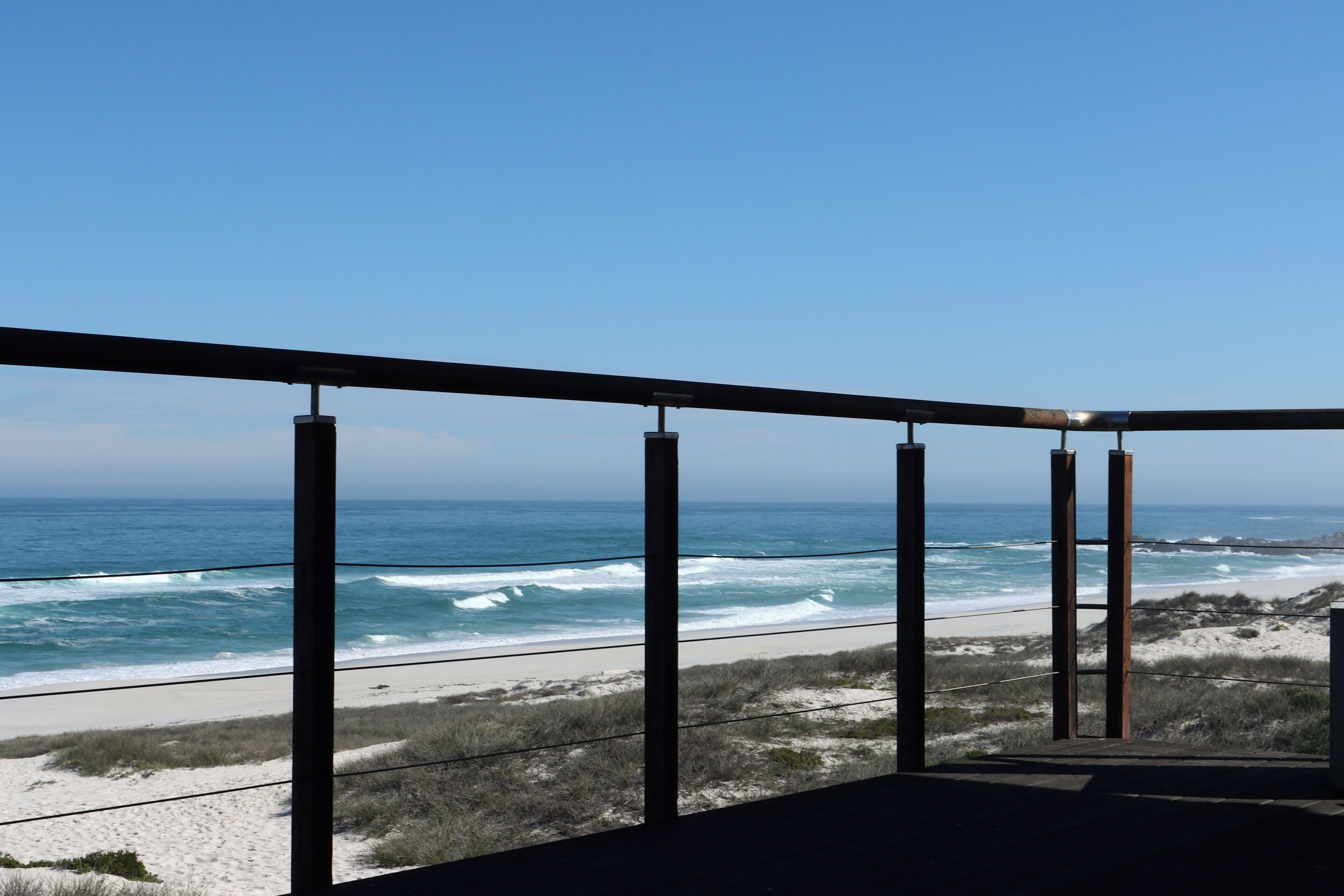 A balcony with a view of the ocean and beach.