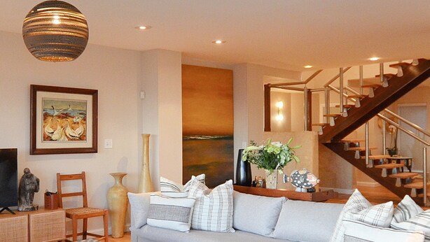 Un salon moderne avec un canapé, une table basse et un escalier.