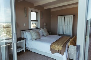 A bedroom with a bed, a nightstand, a window, and a wardrobe.