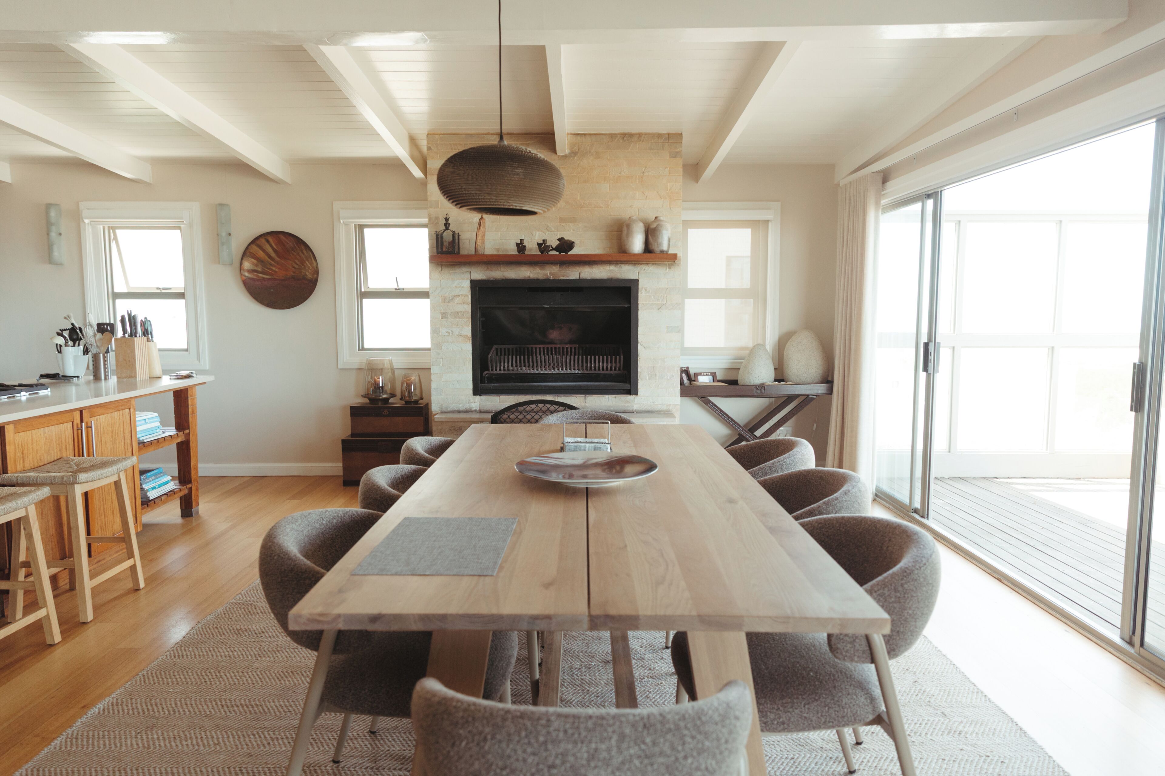 A spacious dining area with a long wooden table and multiple chairs, a fireplace, and a large window providing natural light.