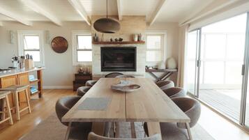 A spacious dining area with a long wooden table and multiple chairs, a fireplace, and a large window providing natural light.