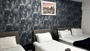 Habitación de hotel con dos camas individuales, un ventanal amplio y un cuadro en la pared.