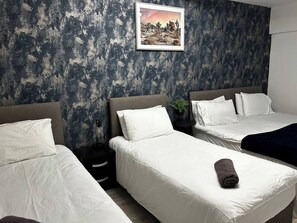 Une chambre d’hôtel avec deux lits simples, une grande fenêtre et un tableau encadré au mur.