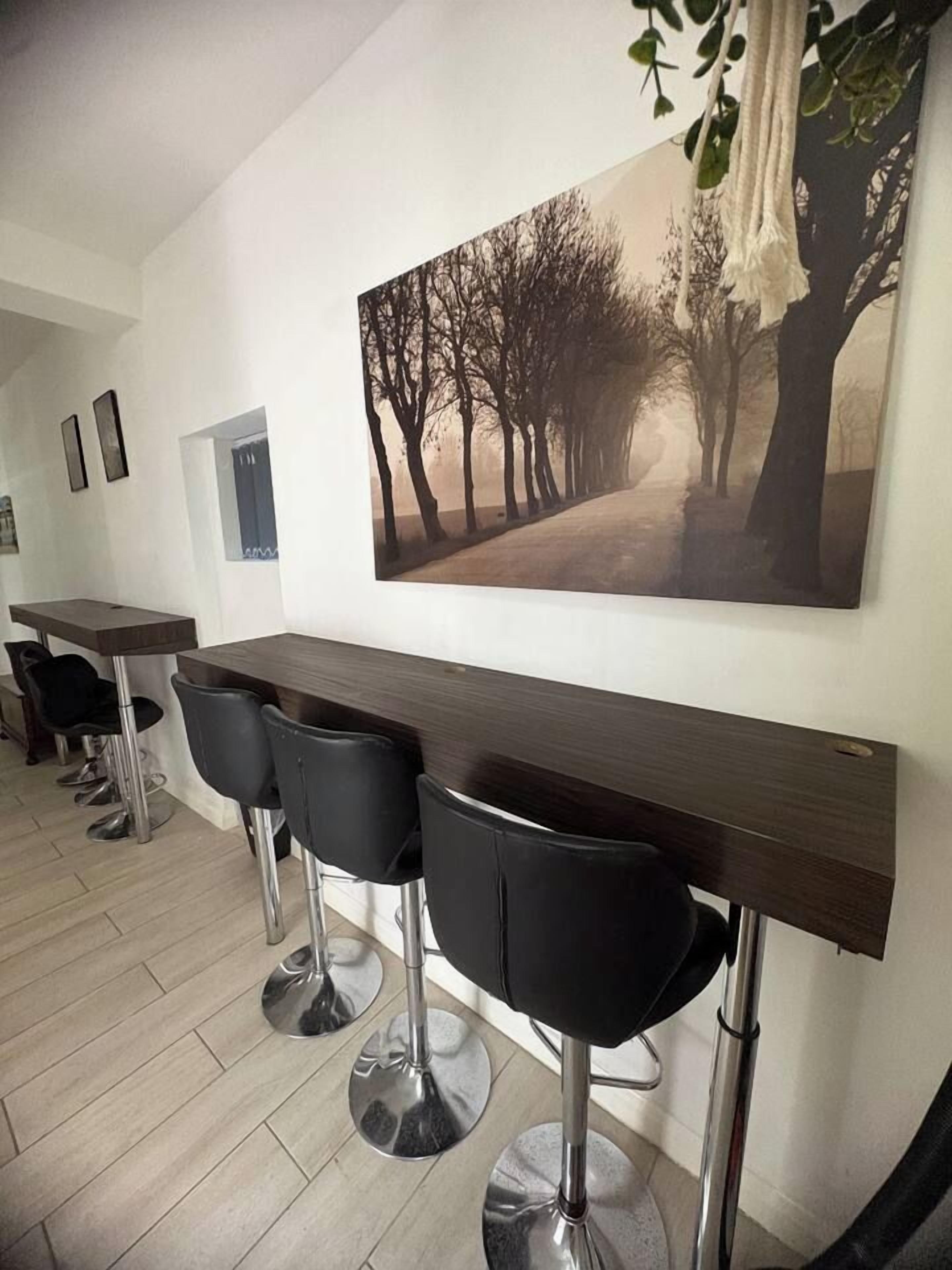 A bar area with a long counter and four black bar stools.
