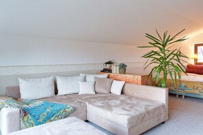 A modern living room with a beige sectional sofa, a coffee table, and a large potted plant. - Holiday home with 3 bedrooms (Groß Zecher)