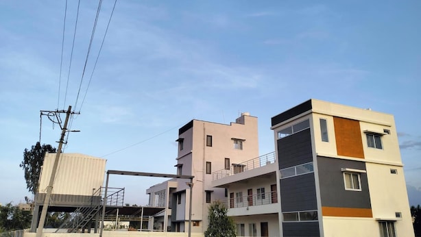 Um edifício residencial de vários andares com telhado plano e uma varanda no segundo andar, com uma estrutura de linha de energia visível.