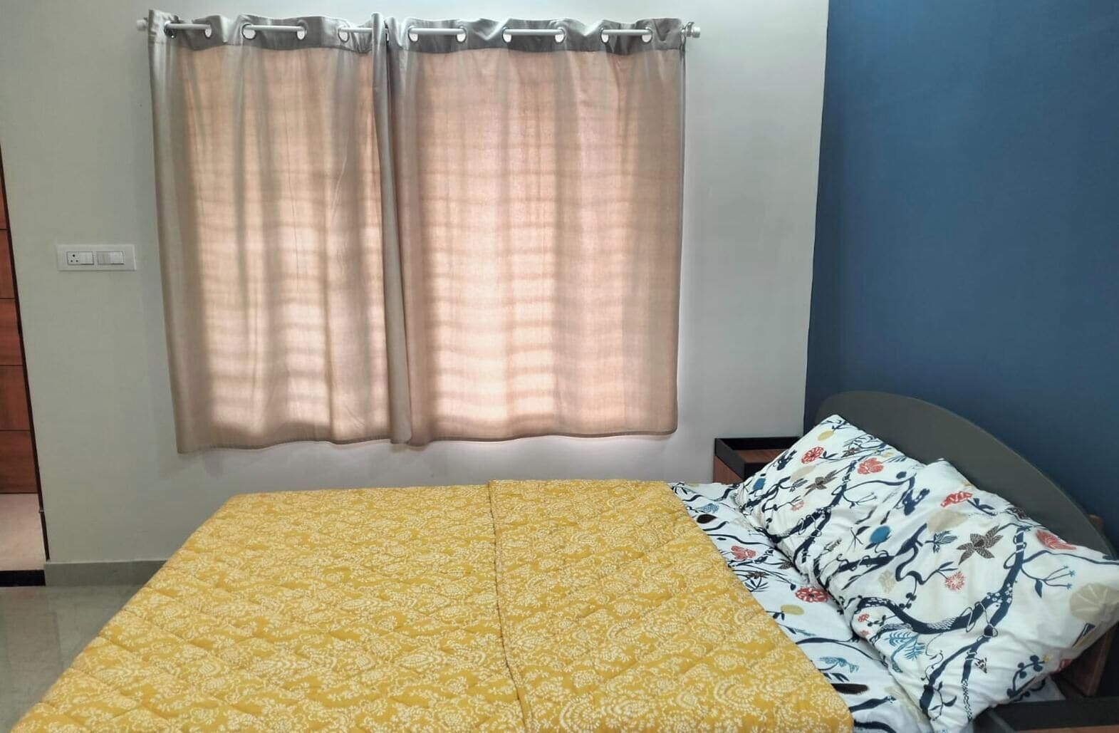 A room with a bed, curtains, and a wall unit.