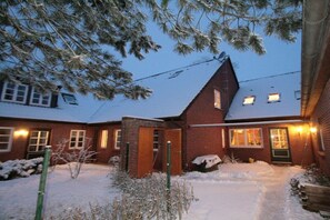 A brick house with a snow-covered yard and a wooden door. - Holiday apartment with 2 bedrooms (Krummhörn-Greetsiel)