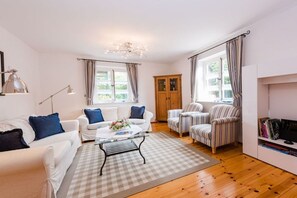 A living room with a white sofa, striped armchairs, a coffee table, and a bookshelf. - Holiday apartment with 2 bedrooms (Krummhörn-Greetsiel)