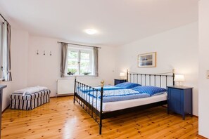 A bedroom with a bed, a nightstand, a window, and a radiator. - Holiday apartment with 2 bedrooms (Krummhörn-Greetsiel)