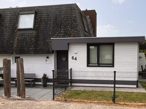 Ein zweistöckiges Wohngebäude mit weißer Fassade und schwarzen Dachschindeln.
