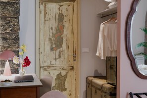 Una habitación con una puerta rústica, un escritorio con una computadora portátil, un espejo y una maleta.