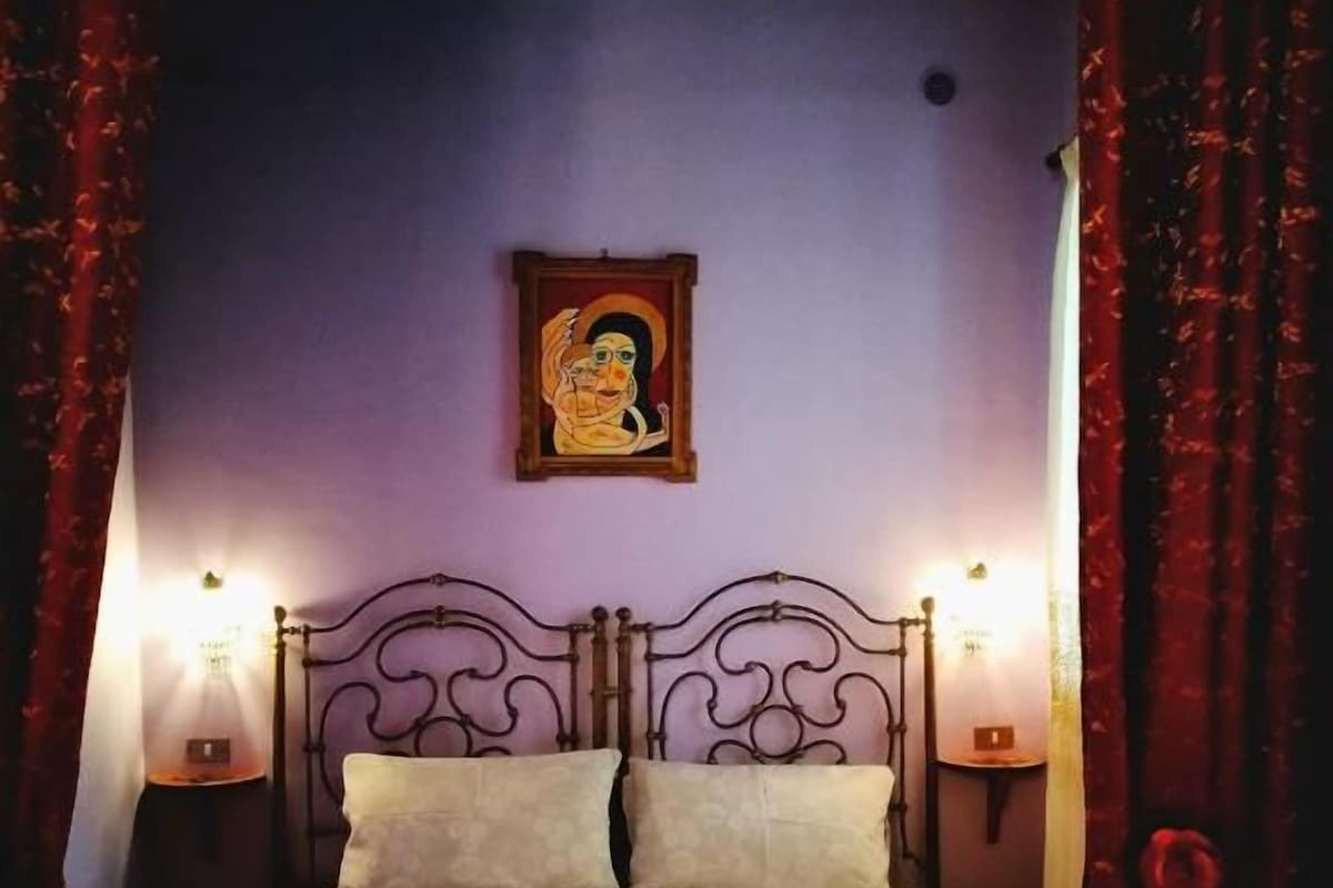 A bed with a headboard, two bedside lamps, and a wall-mounted picture.