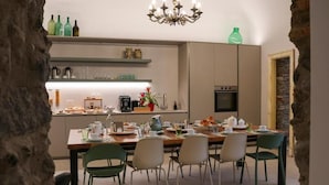 Una cocina moderna con comedor, una araña y una pared de piedra.