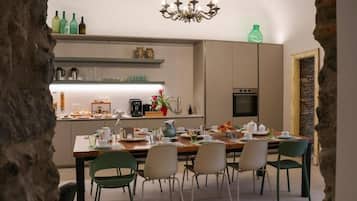 Una cocina moderna con comedor, una araña y una pared de piedra.
