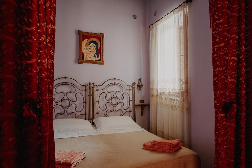 Un letto singolo con testiera in metallo, biancheria bianca e una coperta rossa.