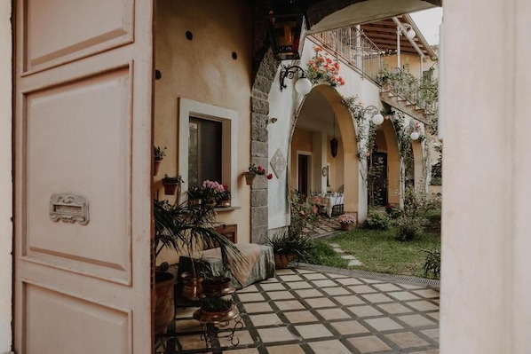 Una entrada con suelo de baldosas, una puerta y un balcón con plantas y flores.