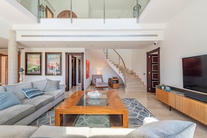 A modern living room with a sofa, coffee table, and a TV on a wooden cabinet. - Can Porquer, Luxury villa with a pool near the golf course (IB Pollensa)