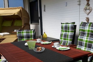 Un espace patio avec une table pour deux, des meubles en osier et un mur décoratif.
