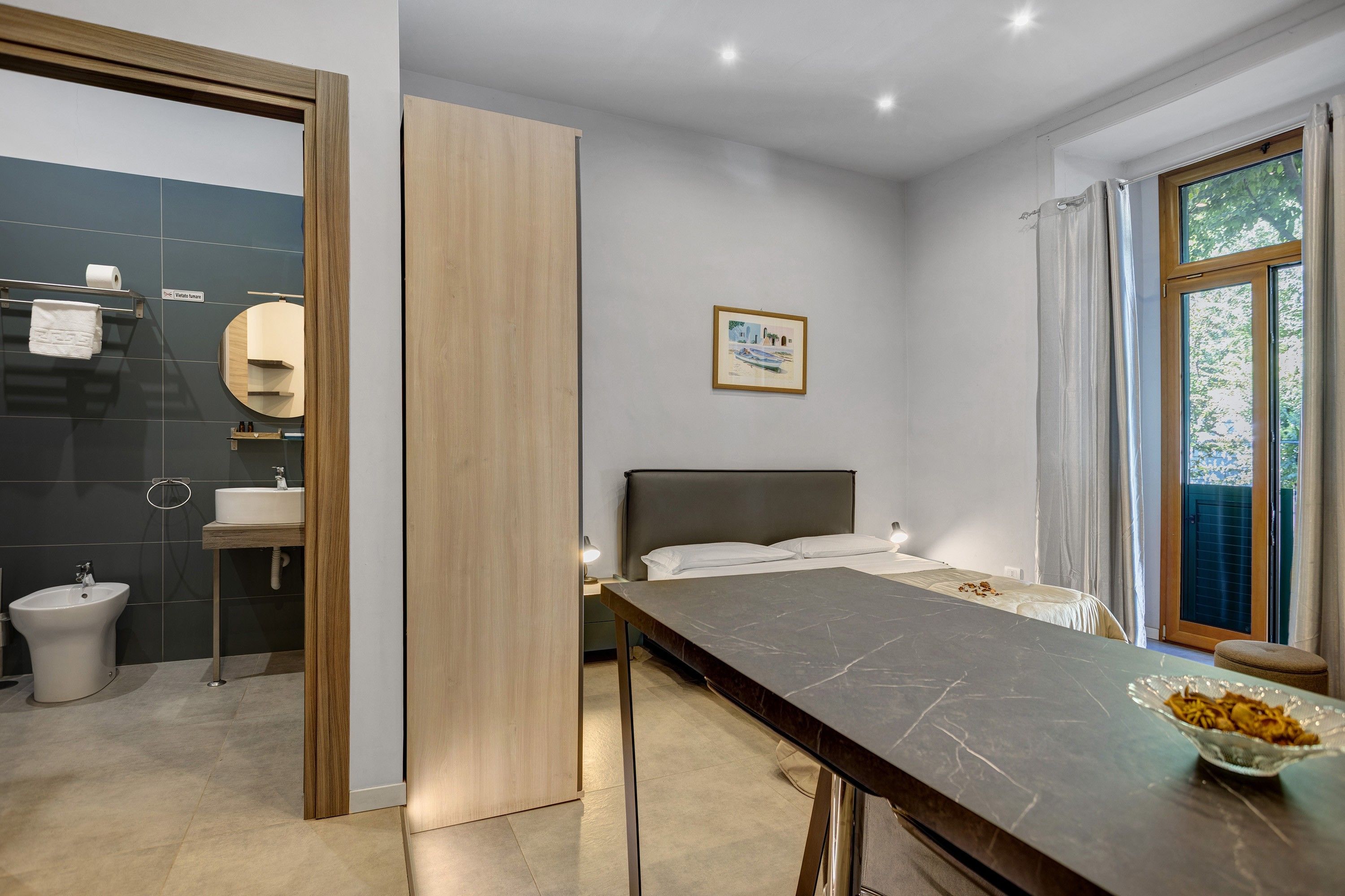 Une chambre d’hôtel moderne, équipée d’un lit, d’une table de chevet et d’une fenêtre avec des rideaux.
