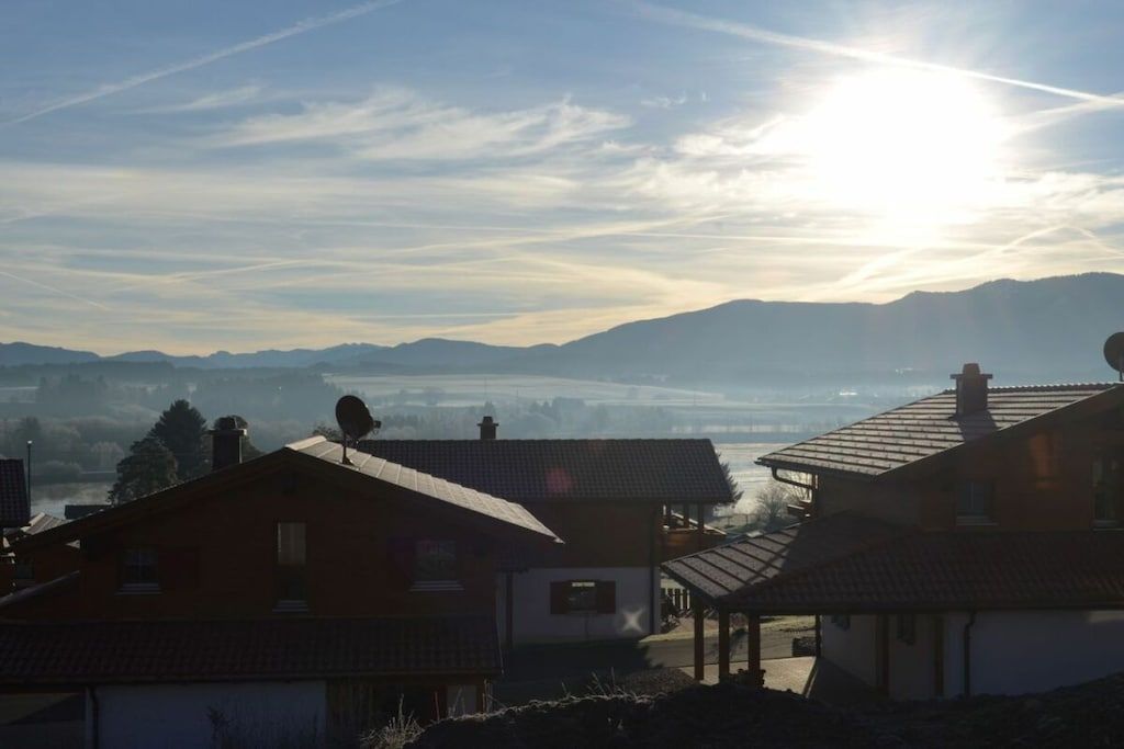 Ein Wohngebiet mit Häusern, blauem Himmel und Bergen im Hintergrund.
