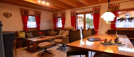 Una sala de estar acogedora con techo de madera, un sofá, una mesa de comedor y una chimenea.