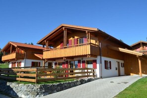 A chalet-style building with a wooden facade, multiple balconies, and a stone wall in front. - Holiday home in Allgäu with 3 bedrooms (Lechbruck am See)