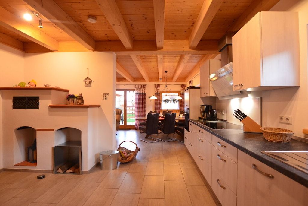A kitchen with wooden beams, a dining area with a table and chairs, and a fireplace.