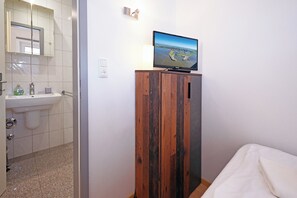 A bathroom with a sink, mirror, and a television mounted on a wooden cabinet. - Meerliebe by Flo & Kim: Your modern apartment just 300 meters from the North Sea beach (Büsum)