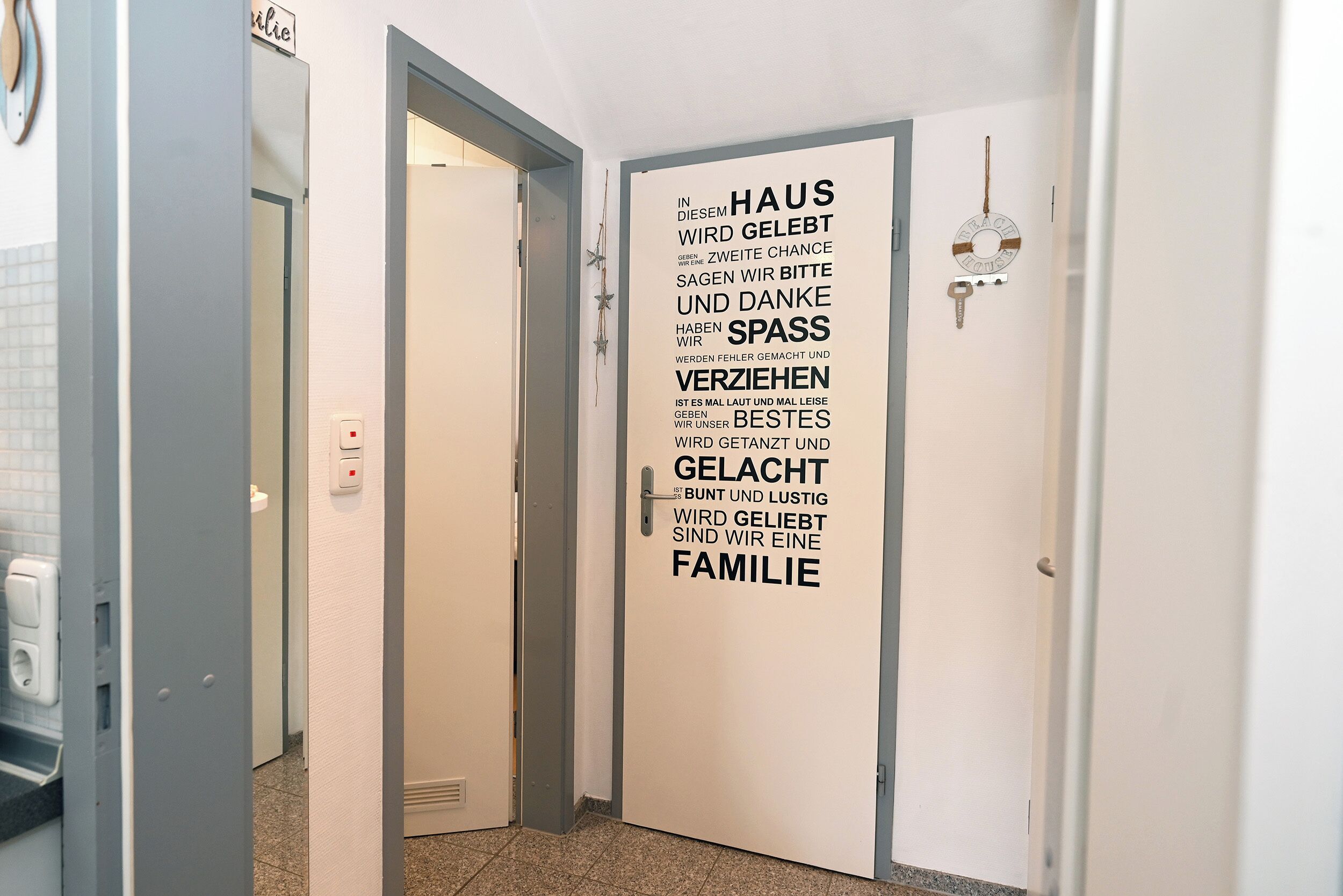 Un pasillo con una puerta que muestra un mensaje de texto en alemán sobre la familia y la gratitud.