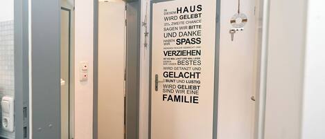 Un pasillo con una puerta que muestra un mensaje de texto en alemán sobre la familia y la gratitud.