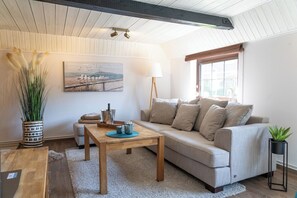 Ein gemütliches Wohnzimmer mit einer Couch, einem Couchtisch und einem Gemälde an der Wand.