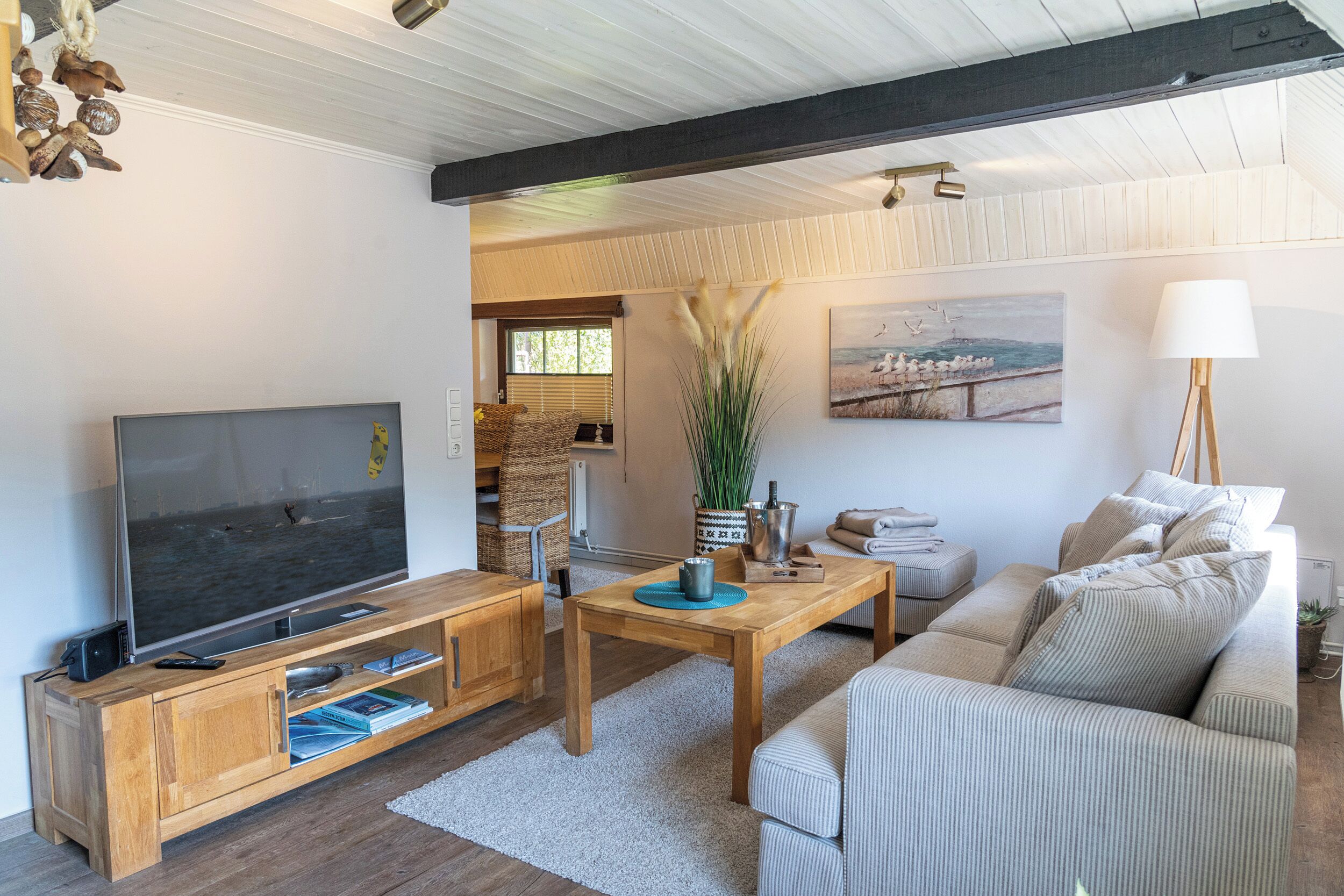 Ein Wohnzimmer mit Fernseher, Holzmöbeln, einem Gemälde und einer Lampe.