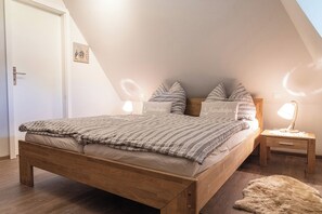Makuuhuoneessa on puinen sänky, raidallinen vuodevaatteisto, kaksi yöpöytälamppua ja pehmeä matto.