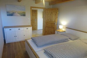 Une chambre avec deux lits, une armoire en bois, une table de chevet avec une lampe et un tableau au mur.