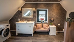 Une salle de bain moderne dotée d’un grand meuble-lavabo, d’un lave-linge, d’un porte-serviettes et d’une fenêtre offrant une belle vue.