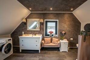 A modern bathroom with a large vanity, a washing machine, a towel rack, and a window with a view. - Country Bliss - Nordhorn (Nordhorn)