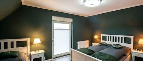 A bedroom with a white bed, two bedside tables with lamps, a window, and a ceiling light.