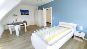 A bedroom with a bed, a desk, and a chair. There is a wardrobe and a door leading to another room. - Holiday apartment Klever Berg (Kleve)