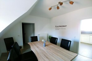 A dining area with a long table, four chairs, and a ceiling light fixture. - Holiday apartment Klever Berg (Kleve)