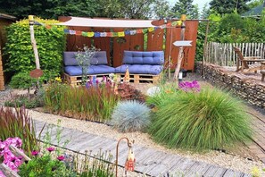 Ein Garten mit einer Holzbank, einem Holzzaun und unterschiedlichen Pflanzen.