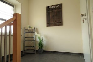 A hallway with a wooden welcome sign, a metal ladder, and a potted plant. - Holiday apartment Klever Berg (Kleve)