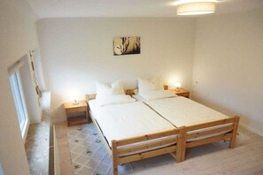 A bedroom with a double bed, bedside tables, a wall-mounted artwork, and a patterned floor. - Holiday farmhouse with 2 bedrooms (Schneverdingen)