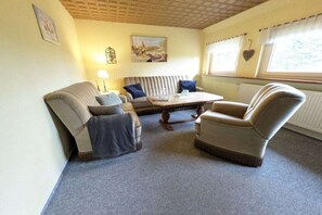 A cozy living room with a sofa, armchair, and a coffee table. - Holiday farmhouse with 2 bedrooms (Schneverdingen)