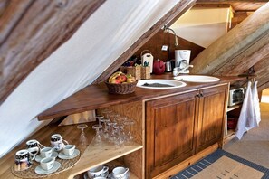 Eine Holz-Kochnische mit Kaffeemaschine, Wasserkocher und Obstkorb.