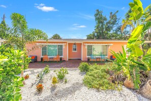 A single-story building with a patio area featuring outdoor seating and a small garden. - Gertrude's Siesta | Private Patio, Pool,  2-min to Beach! 1-min Dining & Music! (Siesta Key)